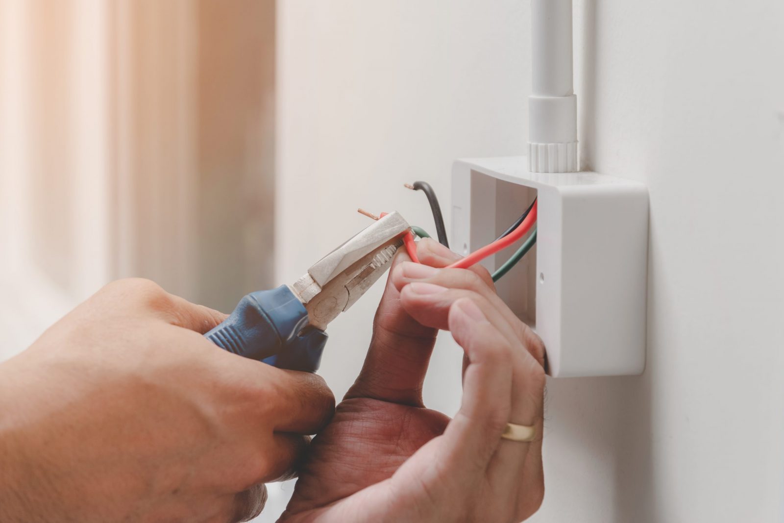 The technician is using a pliers wrench to install the power plug on the wall.